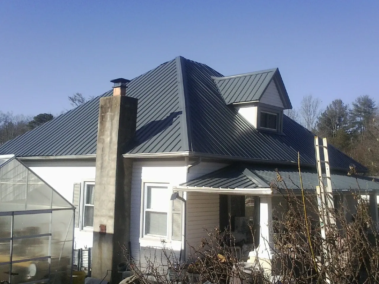 Dark blue standing seam metal roof on a white farmhouse with dormer — Slate & Tile Roof Repair by Roofing Brothers in North Bloomfield