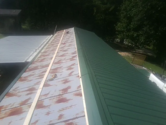 Old rusted panels beside newly installed green metal roofing — Wind Damage Roof Repair by Roofing Brothers in North Bloomfield