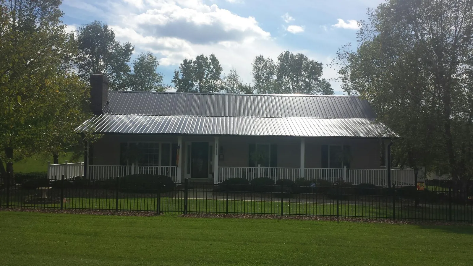 Gray metal roof on a brick ranch with a full width front porch — Gutter Guard Installation work by our crew in North Bloomfield