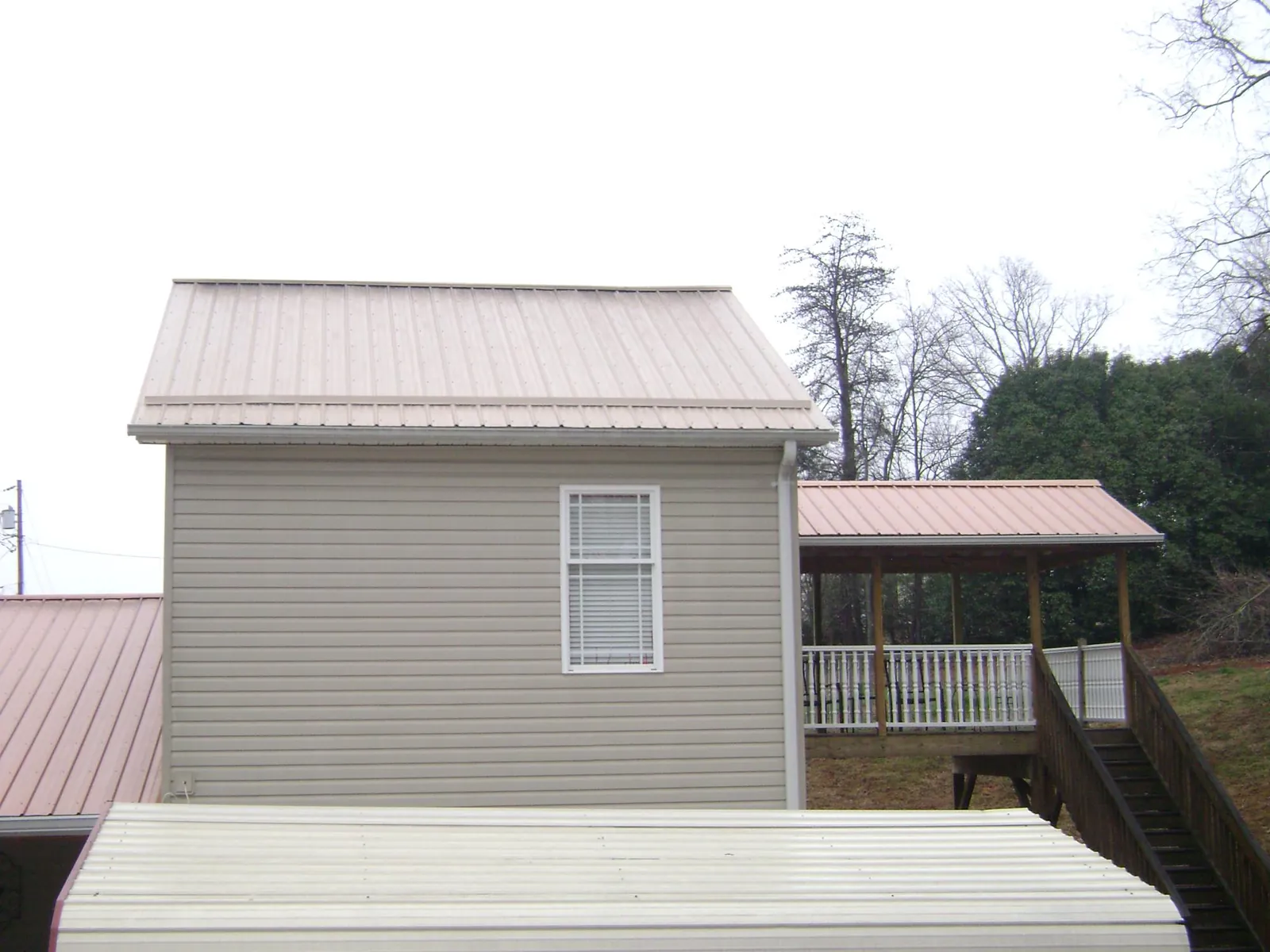 Tan metal roofs on a two story addition and attached porch, from a Roof Replacement job in North Bloomfield